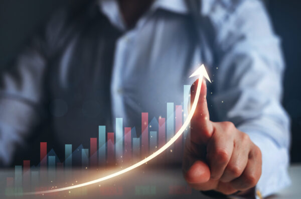 Finger tracing an upward arrow over a bar graph, illustrating rising performance.