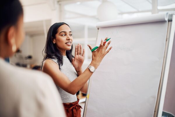Presenter explaining points on a blank flip-chart during a team discussion.