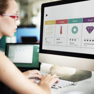 Woman in red glasses assessing skill-level icons on a desktop screen.