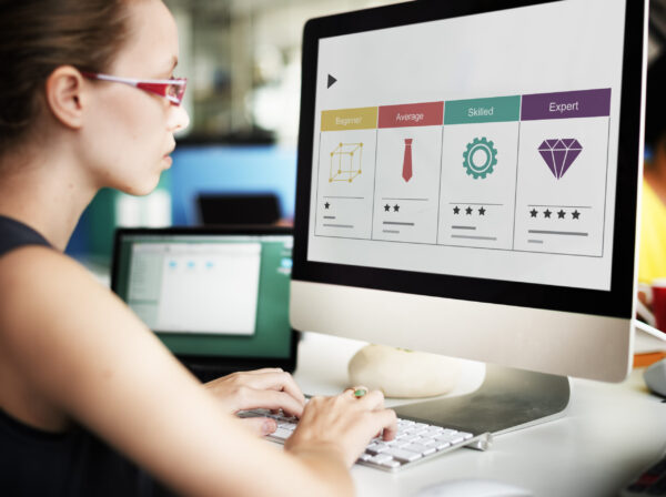 Woman in red glasses assessing skill-level icons on a desktop screen.